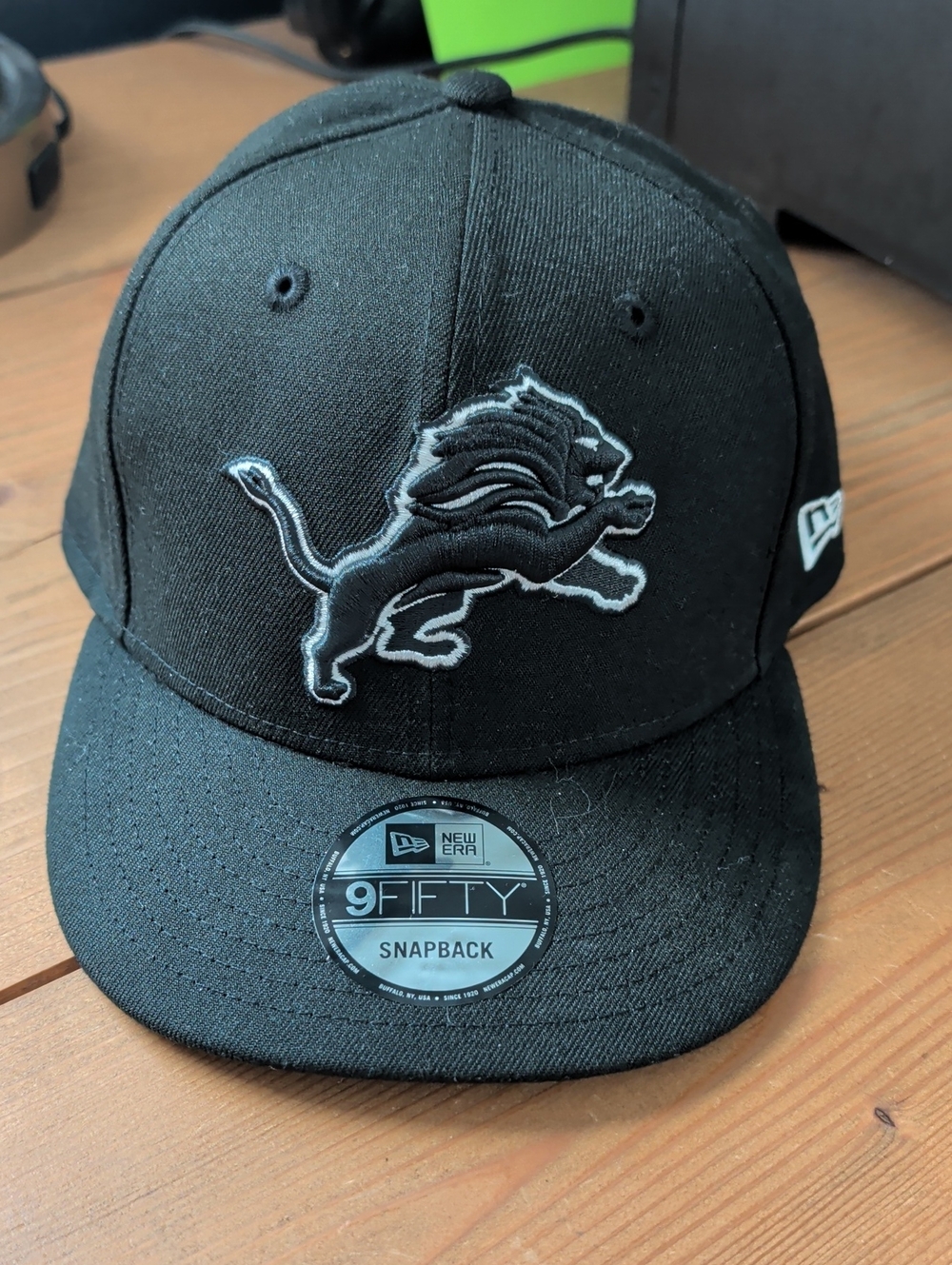 New Era Black Snapback Hat with Gray-Outlined Lion Patch
